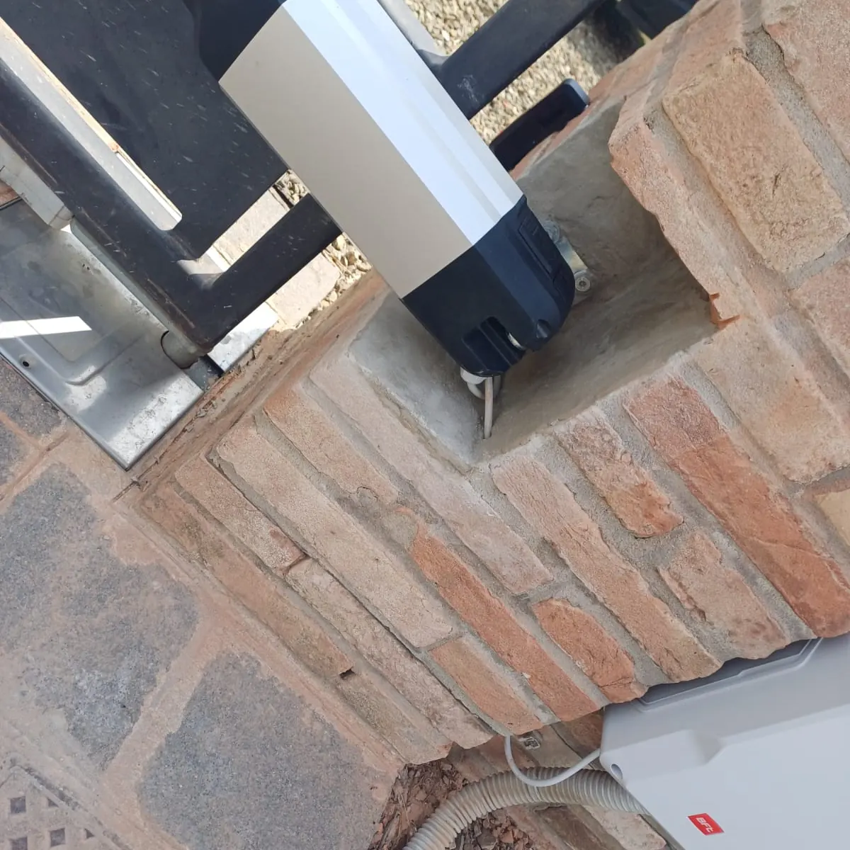 Attuatore BFT installato su un pilastro in mattoni con la centrale di comando