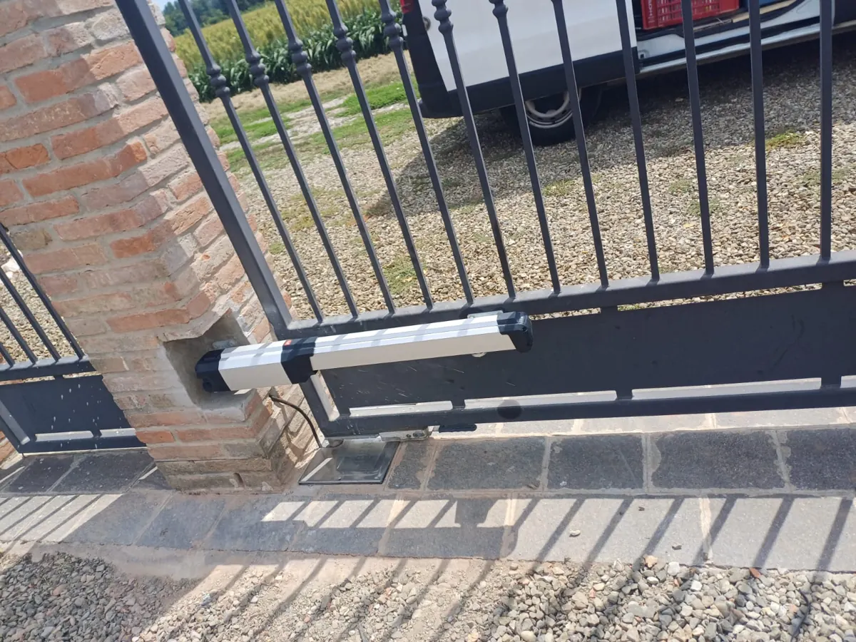 Attuatore lineare montato alla base di un cancello a battente in ferro