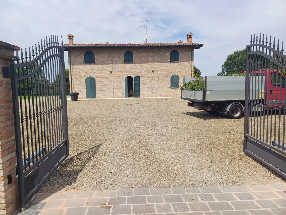 Cancello a battente automatizzato aperto sul cortile di una casa di campagna