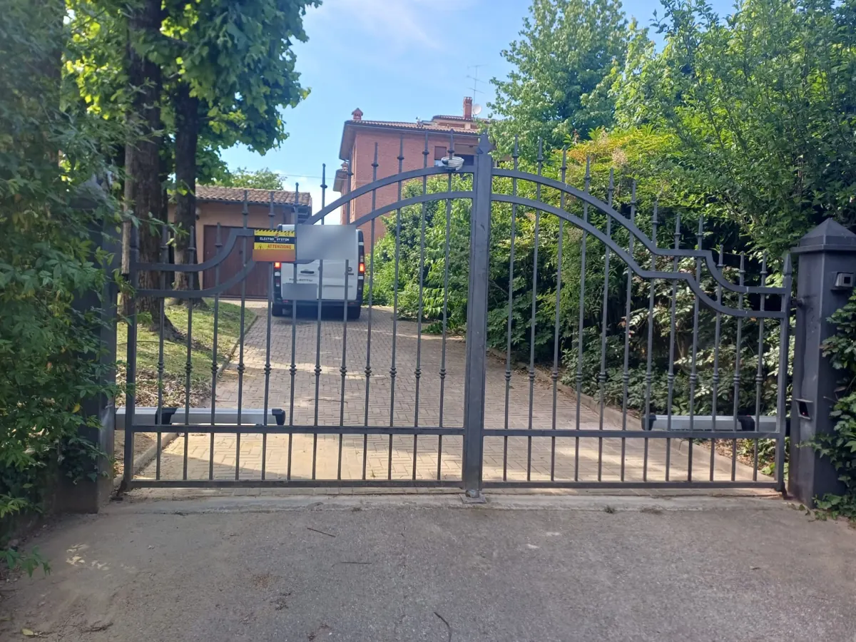 Cancello automatico a due ante su un ingresso carrabile con cartello di segnalazione